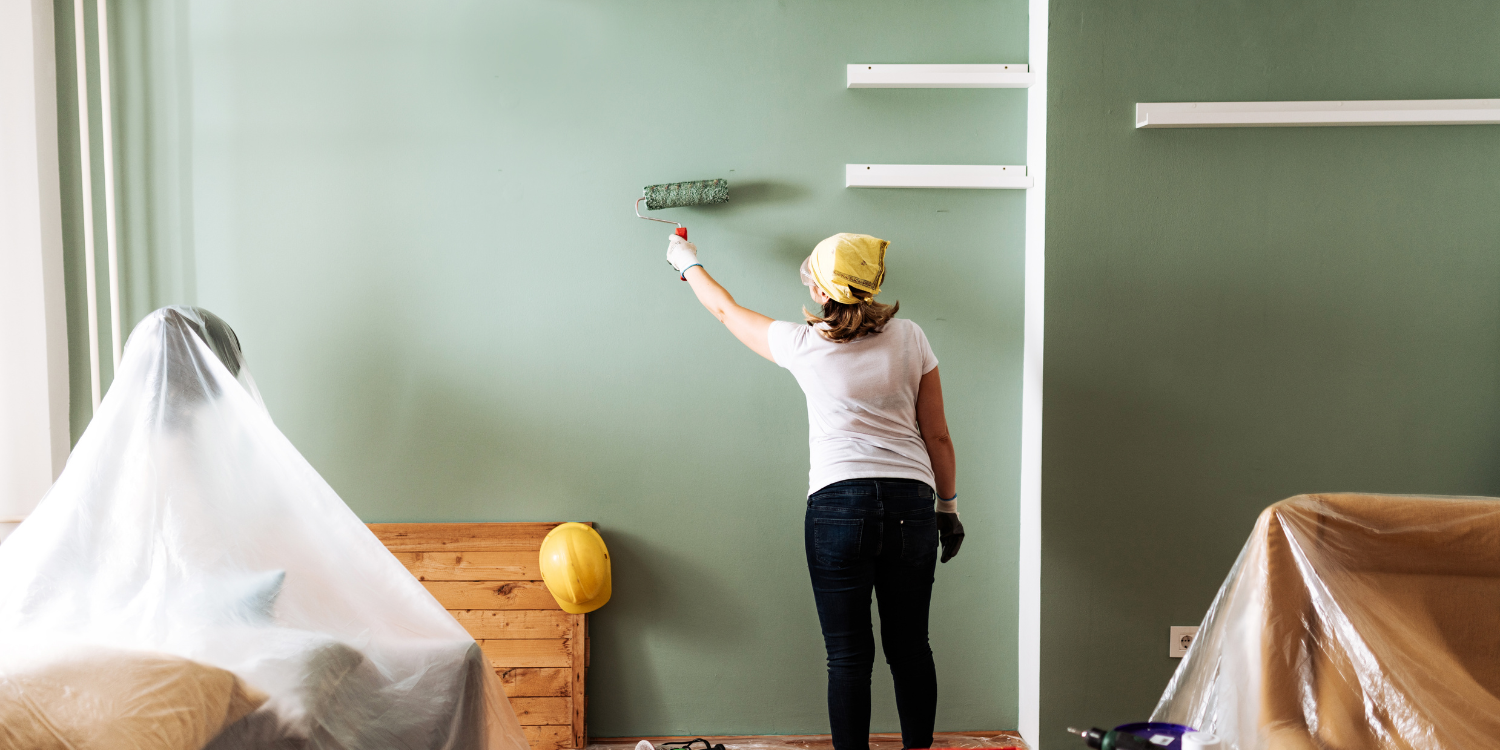woman painting a wall green